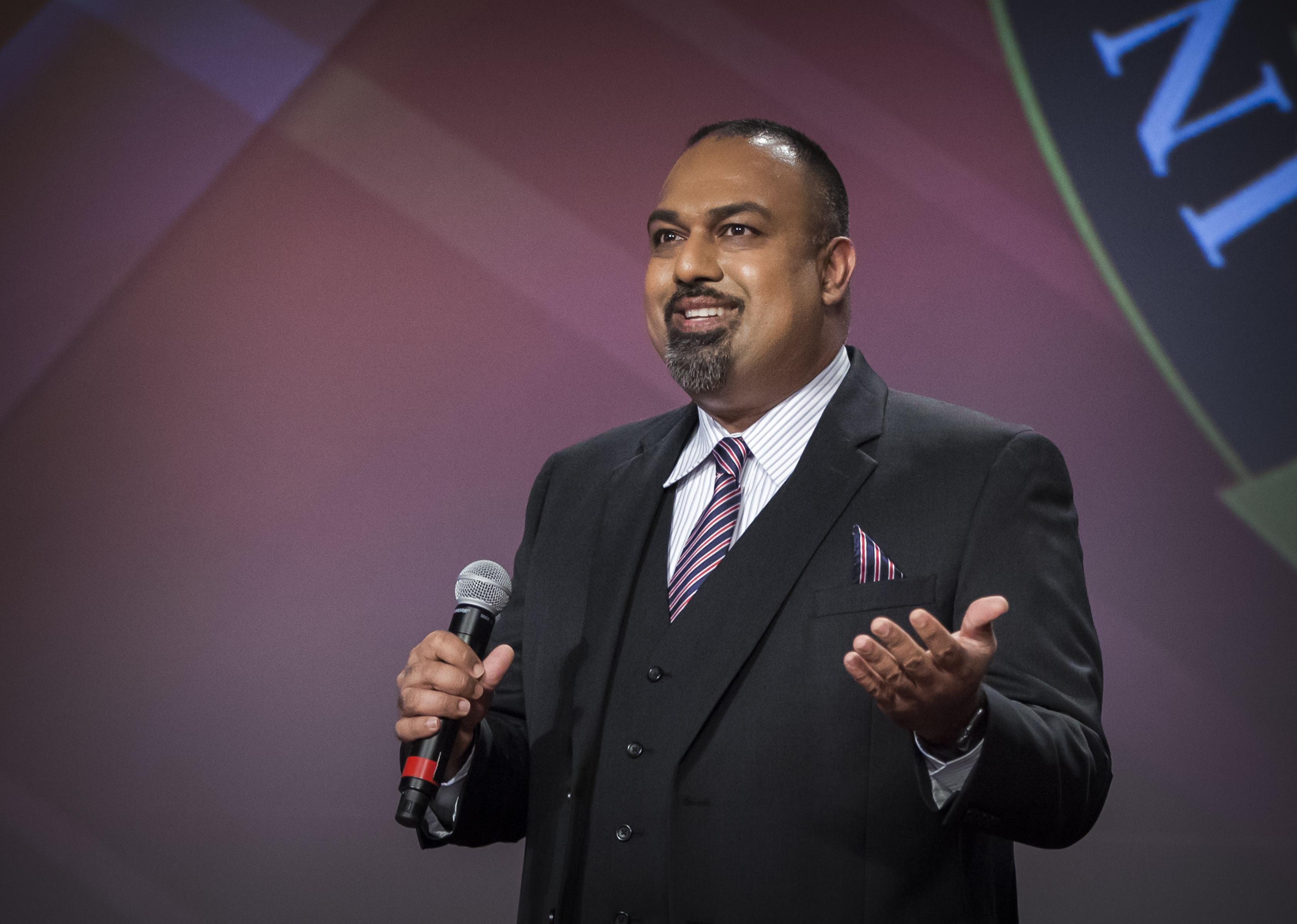 Executive Coach Sunil Harrypersad on the stage speaking to the John C. Maxwell